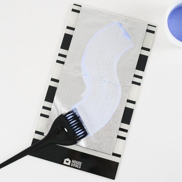 Lightener swiped across the Retro Stripe balayage board with a black color brush and bowl