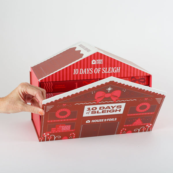 Hand holding the closed 10 Days of Sleigh gingerbread house advent calendar box