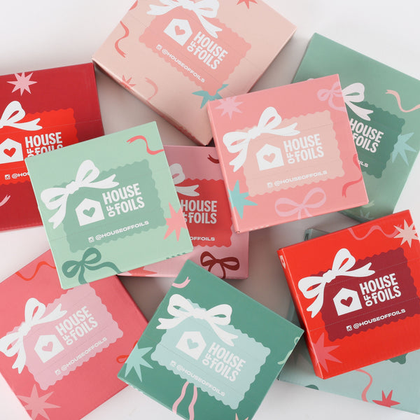 The ten House of Foils mystery foil boxes from the advent calendar scattered in red, pink, sage and mint