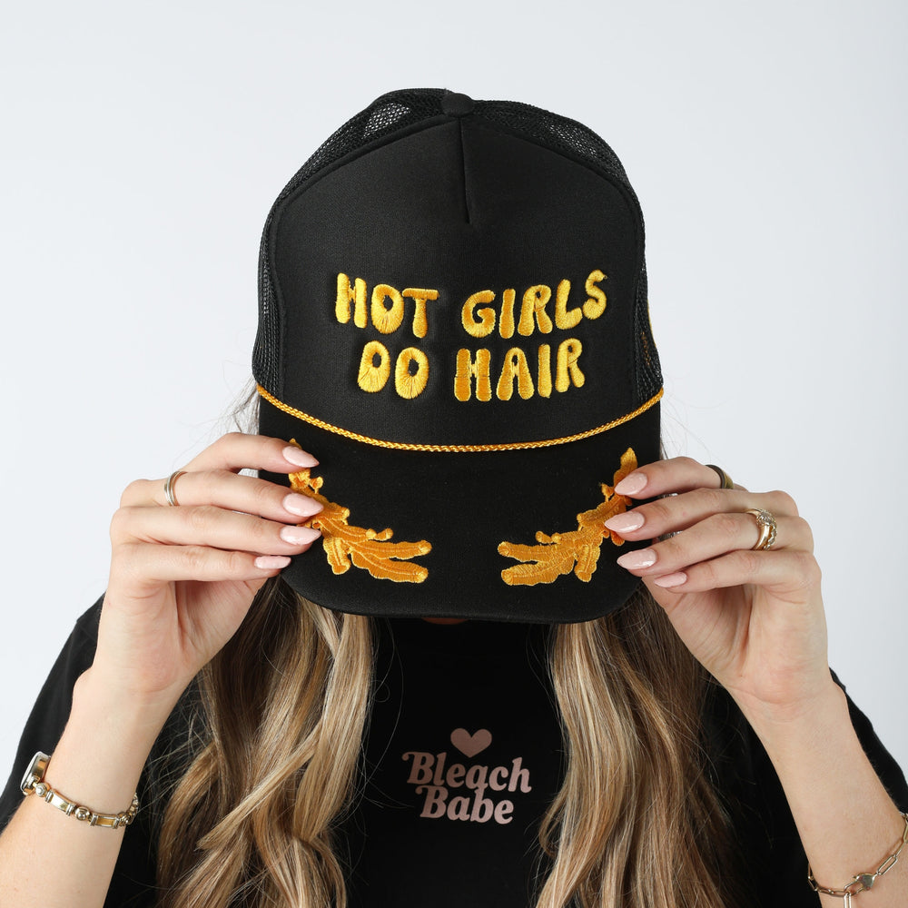 Model wearing the black Hot Girls Do Hair trucker hat with yellow puff embroidery