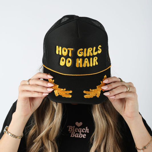 Model wearing the black Hot Girls Do Hair trucker hat with yellow puff embroidery