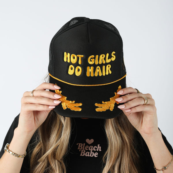 Model wearing the black Hot Girls Do Hair trucker hat with yellow puff embroidery