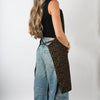 Side view of the cheetah print HOF Everyday Apron worn over jeans