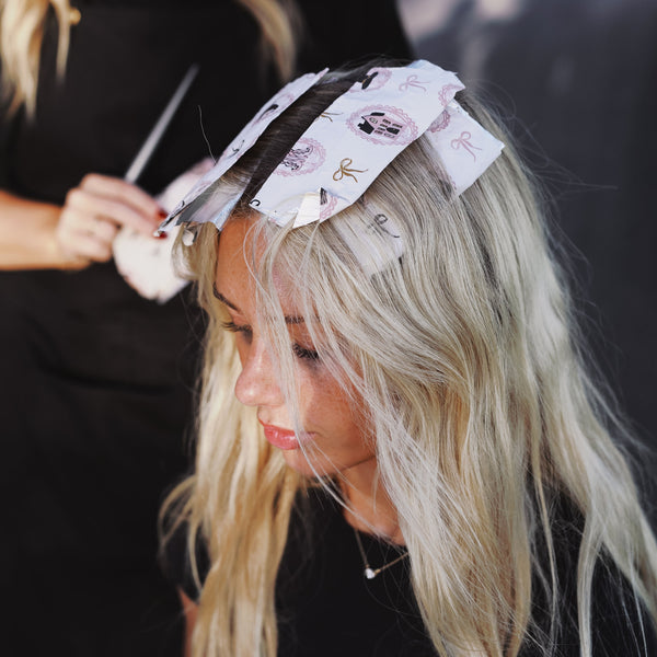 Stylist applying Haunted Mansion foil to a blonde client's hair